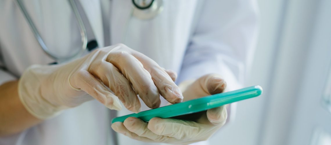 the-doctor-is-holding-a-smartphone-in-gloves-